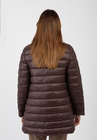 Cappotto imbottito marrone con cuciture orizzontali, caratterizzato da una texture lucida e liscia e un taglio dritto, che arriva fino a metà coscia.