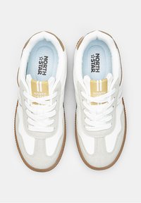 White and gray sneakers with a suede and synthetic upper, featuring a small yellow accent, round toe, and textured gum rubber sole.