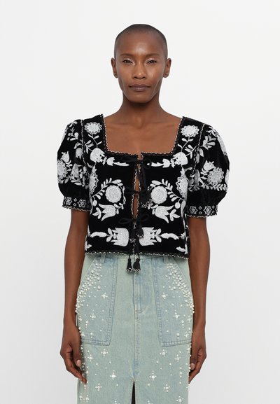 Black velvet cropped top with white floral embroidery, puff sleeves, square neckline, and tied front closure with tassels.