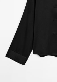 Zwarte longsleeve met een gladde textuur, een rechte snit en een satijnen manchet. Eenvoudig ontwerp zonder extra patronen of accenten.