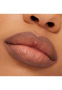 Matte huulipuna on levitetty huulille; luonnollinen ihonsävy alla. Huulissa on pehmeä gradientti vaaleasta tummanruskeaan, ja pinnassa on teksturoitu lopputulos.