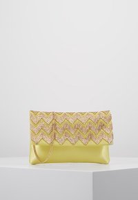 Kabelka v žluté ekokůži s texturovaným zlatým zigzag vzorem na klopě, vybavená odnímatelným řetízkem.