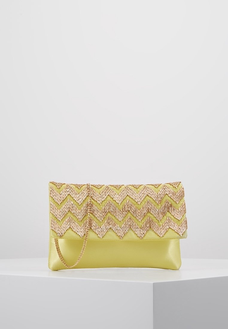 Kabelka v žluté ekokůži s texturovaným zlatým zigzag vzorem na klopě, vybavená odnímatelným řetízkem.