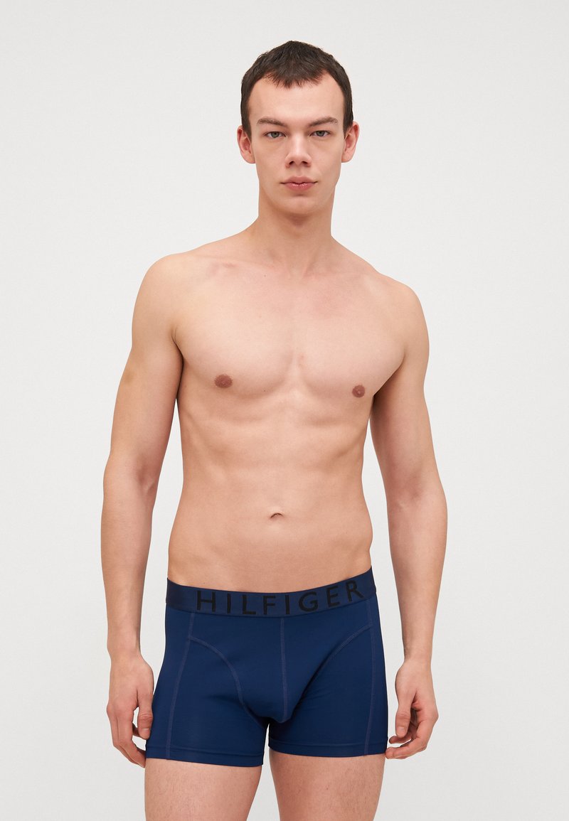 Boxers en coton bleu marine avec une ceinture noire portant le logo 'HILFIGER'. Texture lisse, design ajusté et longueur de jambe courte.