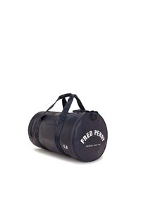Borsa a cilindro blu navy con doppi manici e tracolla. Presenta il testo bianco "FRED PERRY" e il logo. Realizzata in materiale liscio e resistente.