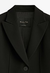 Black blazer featuring notched lapels, single button closure, and label reading "Massimo Dutti, Made in Portugal." Smooth fabric texture.