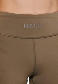 Olijfgroen leggings met een hoge tailleband, voorzien van een "HALO" logo in lichtgrijs. Zachte textuur en platte naden voor comfort.