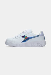 Fehér sneaker, sima textúrával, több színben csillogó csíkkal és kiemelkedő fehér talppal, amelyen a "diadora" felirat van megnyomva.