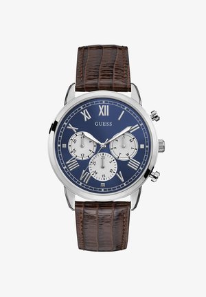 Zegarek chronograficzny z niebieską tarczą, srebrnymi cyframi rzymskimi i trzema sub-tarczami. Skórzany pasek w brązowym kolorze z wzorem krokodyla, stalowa koperta.