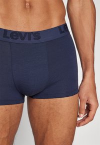 Sötétkék pamut boxernadrág, textúrázott Levi's logós derékkal. Szoros illeszkedés és sima, varrás nélküli dizájn jellemzi.