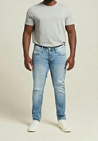 Vaaleansiniset slim fit -farkut, haalistunut etupuoli, viisi taskua ja keskikorkea vyötärö, yhdistettynä harmaaseen pyöreäkaulaiseen t-paitaan ja valkoisiin tennareihin.