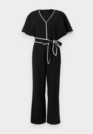 Μαύρη ολόσωμη φόρμα με φαρδιές κοντές μανσέτες, λευκή διακόσμηση στα άκρα, V-λαιμόκοψη και ζώνη που δένεται σε φιόγκο στη μέση.