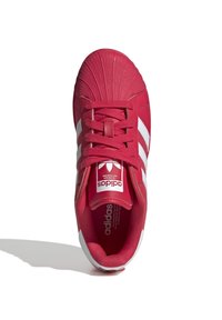 Röd Adidas-sneaker med vita ränder, texturerad tåhätta, snörning knuten och Adidas-logga på tungan, sedd uppifrån mot vit bakgrund.