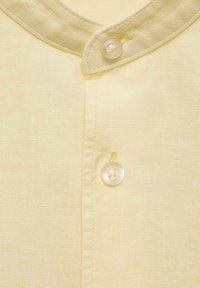 Lichtgele shirtstof met een gladde textuur, met een knoopsluiting en een afgeronde kraagontwerp.