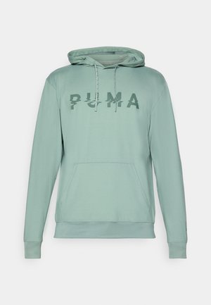 Világos zöld kapucnis pulóver kenguruzsebbel, a mellkasán egy textúrált "PUMA" logóval és a kapucnihoz tartozó zsinórokkal.