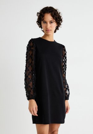 Black dress with a fitted bodice and sheer black fabric sleeves adorned with textured floral appliqués. Simple crew neckline and above-knee length.