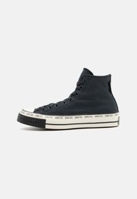 Tumed sinised kõrgekvaliteedilised sneakersid, millel on must kummist tald, ja GORE-TEX bränding valgel ribal alusel.