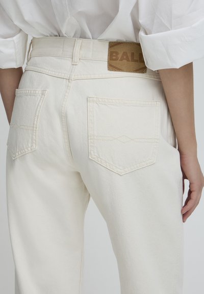 Pantalons en denim blanc à coupe droite, avec une étiquette en cuir marron marquée "BAL" à la taille et deux poches à l'arrière.