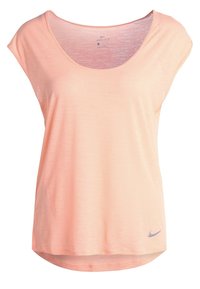 Camiseta Dri-FIT color melocotón con un ajuste holgado, escote redondo, mangas cortas y una textura sutil. Cuenta con un pequeño logo de Nike en gris en el dobladillo.