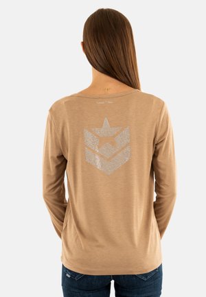 Camicia a maniche lunghe di colore marrone chiaro con un disegno geometrico a stella e a-chevron argentato e lucido sulla schiena. Tessuto morbido con una vestibilità rilassata.
