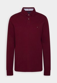 Bordeaux langermet polo shirt med krave, to knapper og en stribet inderside. Har et lille logo på venstre bryst.