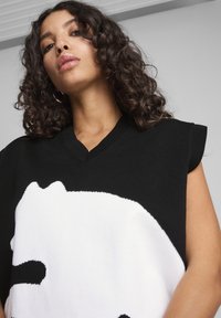 Maglione oversize senza maniche in bianco e nero con un grande design grafico. Il materiale sembra essere a maglia, con scollatura a V e dettagli a coste.