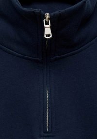 Fleece bleu marine zippé avec un col montant, doté d'une fermeture éclair argentée et d'une texture douce. Conçu pour la chaleur et le confort.