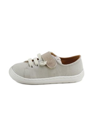 Zapatilla infantil de tela gris claro con suela blanca, dos cordones elásticos y una tira beige de velcro en el lateral.