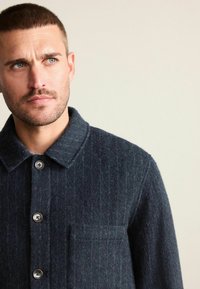 Donkerblauwe wollen shirtjack met een gestructureerde afwerking, grote kraag, vijfknopen sluiting en een borstzak.