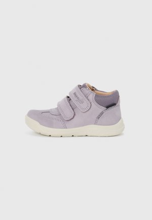 Fioletowe zamszowe buty dziecięce z dwoma zapięciami na rzep, kontrastującym materiałowym obcasem oraz białą gumową podeszwą. Okrągły fason nosa.