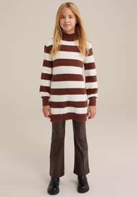 Hnedo-krémový pruhovaný sveter s dlh�ým rukávom a vysokým golierom. Spárované s hnedými topánkami z umelého koženého materiálu s širokými nohavicami a čiernymi členkovými čižmami.
