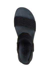 Sandalia negra con dos correas de tela texturizada, suela de goma moldeada y logo de la marca grabado en la plantilla. Diseño plano y abierto.