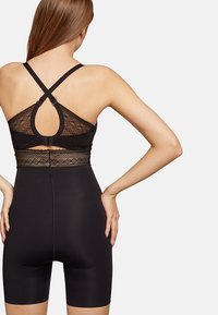 Body shaper nero con dettagli in pizzo in vita e un design a spalline incrociate, caratterizzato da una texture liscia e ganci regolabili.