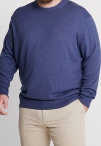 Maglione blu a girocollo realizzato in morbido tessuto a maglia. Caratterizzato da polsini e orlo a coste, con un piccolo dettaglio del logo sul lato sinistro del petto.