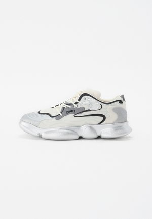 Silver and cream sneaker with a textured upper, black accents, and a rounded, chunky sole featuring distinctively shaped pods.