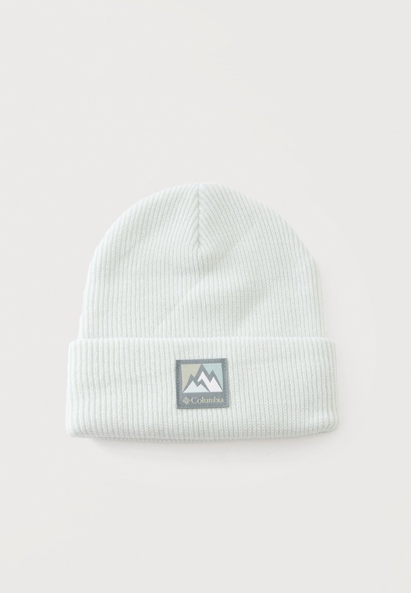Bonnet en tricot côtelé blanc avec revers plié et écusson de la marque Columbia présentant un motif de montagne sur le devant au centre.