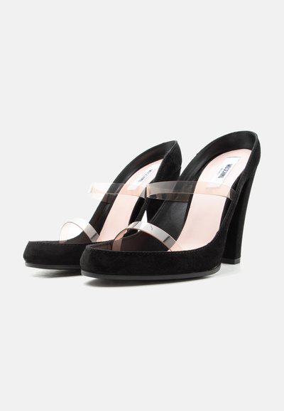 Μαύρες ψηλοτάκουνες γόβες με διαφανείς λουριά στα δάχτυλα των ποδιών και στο μέσο του ποδιού, και ροζ ένθετο πάτου με ορατή ετικέτα εμπορικού σήματος.