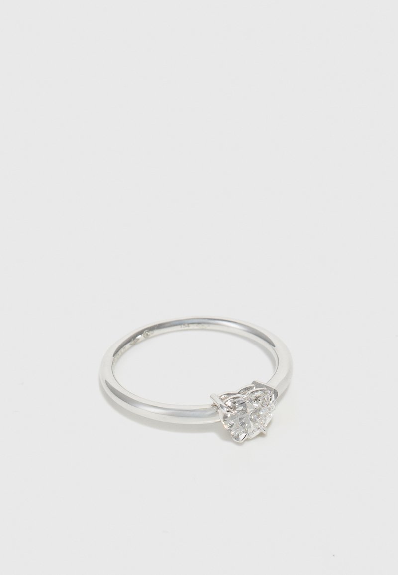 Anillo de plata con una piedra preciosa transparente en forma de corazón, engastada en un ajuste de garras, con una banda lisa y un acabado pulido.