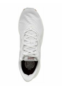 Zapatilla deportiva blanca con parte superior de malla, cordones planos, punta redonda y plantilla con patrón. Presenta un logo y sutiles acentos en color beige.