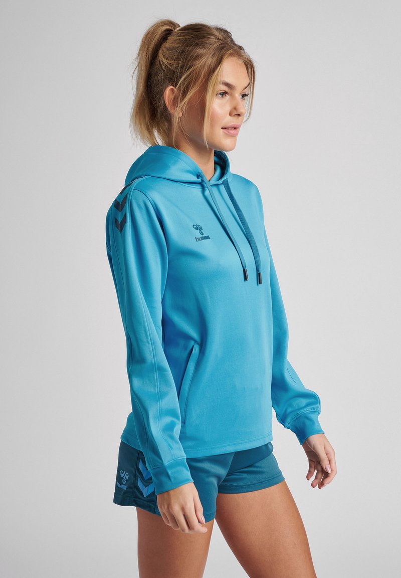 Felpa leggera blu con cappuccio regolabile, con logo nero e dettagli a chevron sulle maniche. Tessuto liscio e vestibilità rilassata.