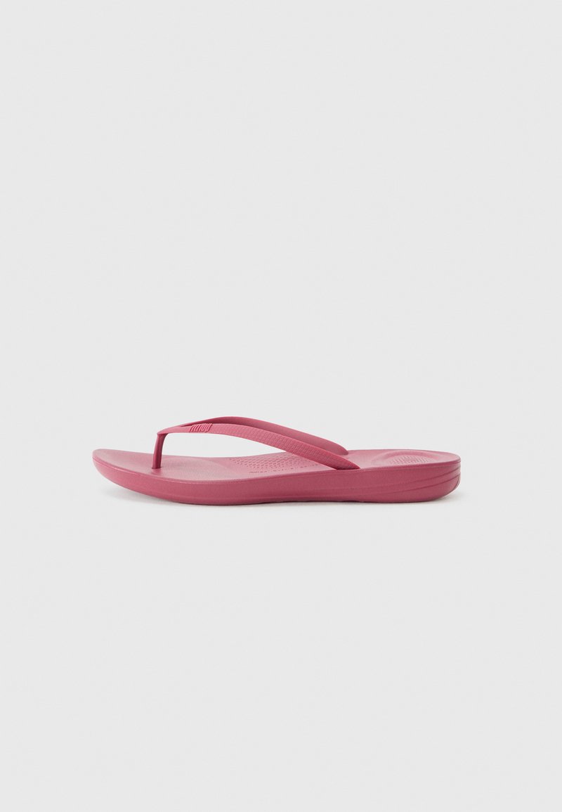 Chinelo feito de borracha rosa, com sola plana, tiras finas em forma de Y e uma palmilha texturizada para melhor aderência.