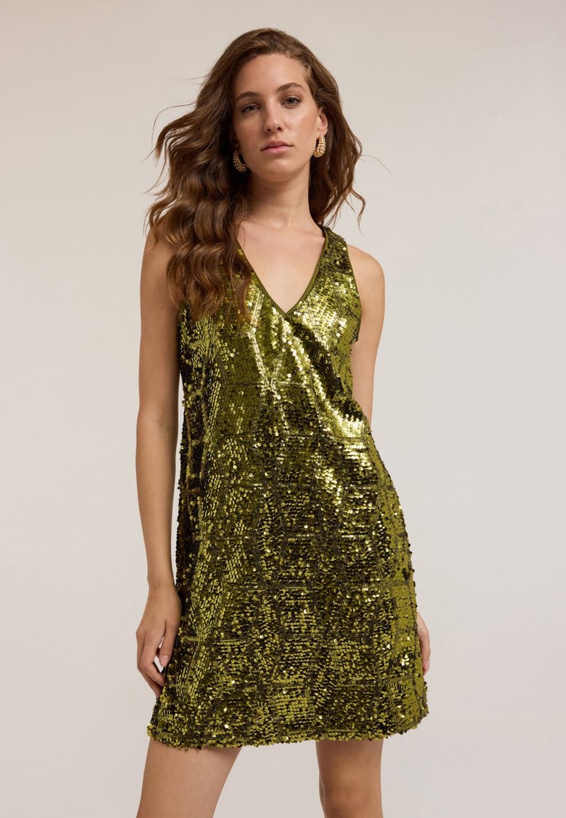 Rochie mini verde cu paiete, cu decolteu în V și fără mâneci. Prezintă un model texturat de paiete strălucitoare, care se suprapun.