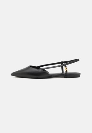 Chaussure plate slingback noire à bout pointu avec double bride et une petite boucle décorative dorée sur le côté.