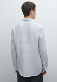 Light gray long-sleeve shirt with a subtle vertical stripe pattern, buttoned cuffs, and a classic collar. Smooth texture and relaxed fit.