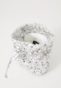 Harmaa paljettipussukka nyöreillä ja pehmeällä vuorella sisältä. Ulkopuoli on tasaisesti peitetty pyöreillä paljeteilla, jotka antavat tekstuurisen ilmeen.