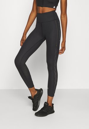 Black high-waisted leggings with textured mesh panels and a diamond pattern. Paired with black athletic shoes.