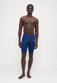 Tengerészkék sportuszoda rövidnadrág rugalmas anyagból, elasztikus derékrésszel és Adidas logóval a bal oldalon.