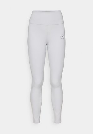 Lichtgrijze legging met een hoge tailleband, een gladde textuur en een klein zwart logo op de linkerdij. Subtiele stiksels overal.