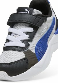 Scarpa sportiva nera, blu e grigia con tomaia in rete, lacci bianchi e cinturino in velcro. Presenta dettagli testurizzati e colletto imbottito.
