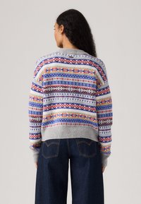 Gebreide trui met een grijze basis en multicolore patronen in rood, blauw, geel en bruin. Geribbelde manchetten en zoom. Ontspannen pasvorm.